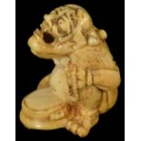 ˜A JAPANESE IVORY NETSUKE OF A PENITENT ONI, LATE EDO PERIOD, CIRCA 1820 seated holding a rosary and