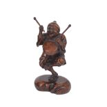 A JAPANESE WOOD FIGURE OF A MAN WITH A DRUM, MEIJI PERIOD (1868-1912) standing on one leg holding