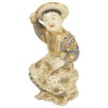 A JAPANESE SATSUMA FIGURE OF A SMILING BOY, MEIJI PERIOD (1868-1912) seated on a rocky mound and