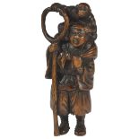 A JAPANESE WOOD NETSUKE OF A STANDING SARUMAWASHI, LATE MEIJI PERIOD, CIRCA 1910 standing with his