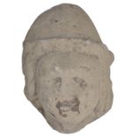 A MEDIEVAL LIMESTONE HEAD, PROBABLY FRENCH, 13TH / 14TH CENTURY carved wearing a cap 27cm high