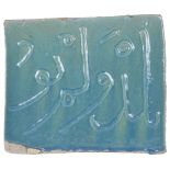 A PERSIAN TURQUOISE GLAZED TILE glazed fritware, of rectangular form, a line of applique relief