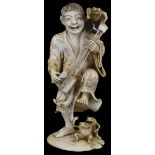 ˜A JAPANESE IVORY OKIMONO OF A MUSICIAN, MEIJI PERIOD (1868-1912) carved playing a samisen and