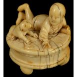 ˜A JAPANESE IVORY NETSUKE OF A BOY AND PUP, MID EDO PERIOD, CIRCA 1750 lying side by side on a