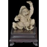 ˜A JAPANESE IVORY OKIMONO OF AN ONI, MEIJI PERIOD (1868-1912) crouching with one arm raised, its
