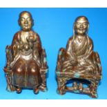 A pair of Chinese porcelain seated figures of Rohan, gilded and splashed blue enamel decoration on