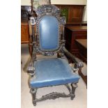 A 19th century heavily carved oak "Gothic Revival" armchair, the seat and back in blue leather