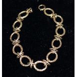 A circular ring link bracelet in bark effect, stamped '9K', 16.7 gm