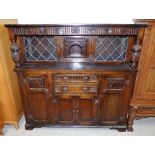 A carved oak buffet sideboard with 2 leaded glass panels and single door over 3 cupboards and 2