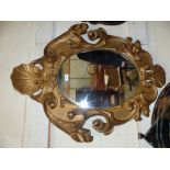 A 19th century wall mirror in gilt oval rococo style shell and scroll frame