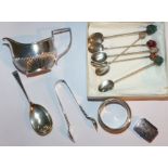 A small silver cream jug (marks worn); a caddy spoon; a pair of sugar tongs; a patch box; a napkin