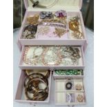 A pink jewellery box containing a small selection of costume jewellery including diamante; beads;