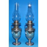 A pair of 19th century silver plated pedestal oil lamps, crested and classical vase shaped, with