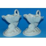 A pair of Royal Worcester white glazed pedestal salt cellars in the form of dolphins with shell