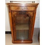 A late Victorian figured walnut music cabinet with shelf and compartments enclosed by glazed door,