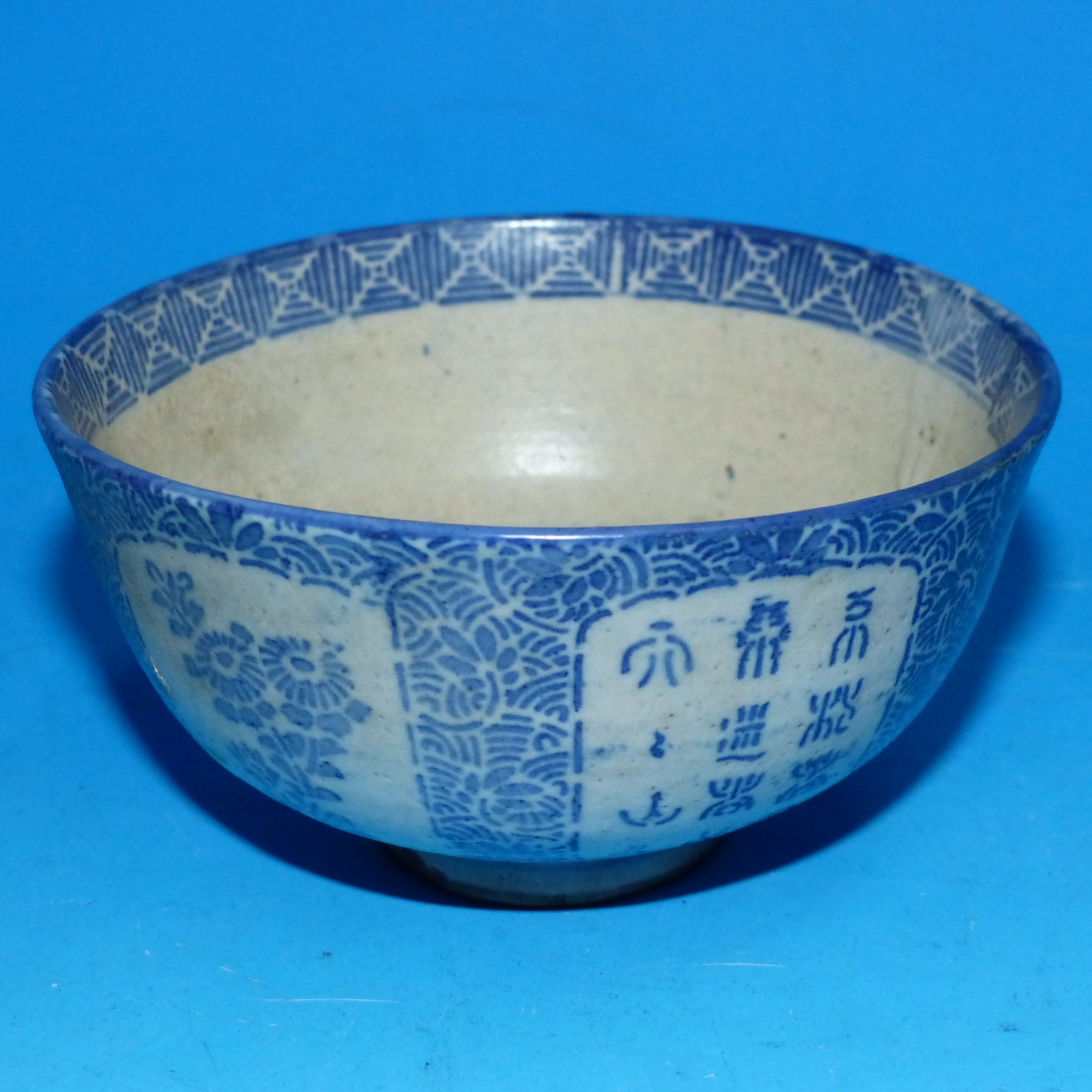 An oriental blue and white tea bowl with panels depicting flowers etc ht 2" width 4"