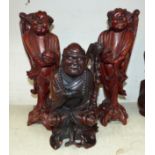 A pair of modern oriental root carvings of men with shells; a similar root carving of a seated