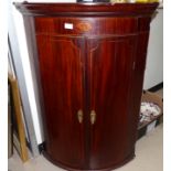 A 19th century mahogany Sheraton style bow front corner cupboard with shell work inlay