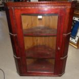 A stained pine corner cupboard with glazed door and interior shelves