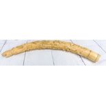 An early 20th century West African carved elephant ivory tusk with a spiral of genre figures,