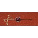 A Victorian yellow metal bar brooch set faceted red stone surrounded by diamond chips (tests as 18