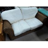 A rattan 2 seater conservatory settee with cream cushions