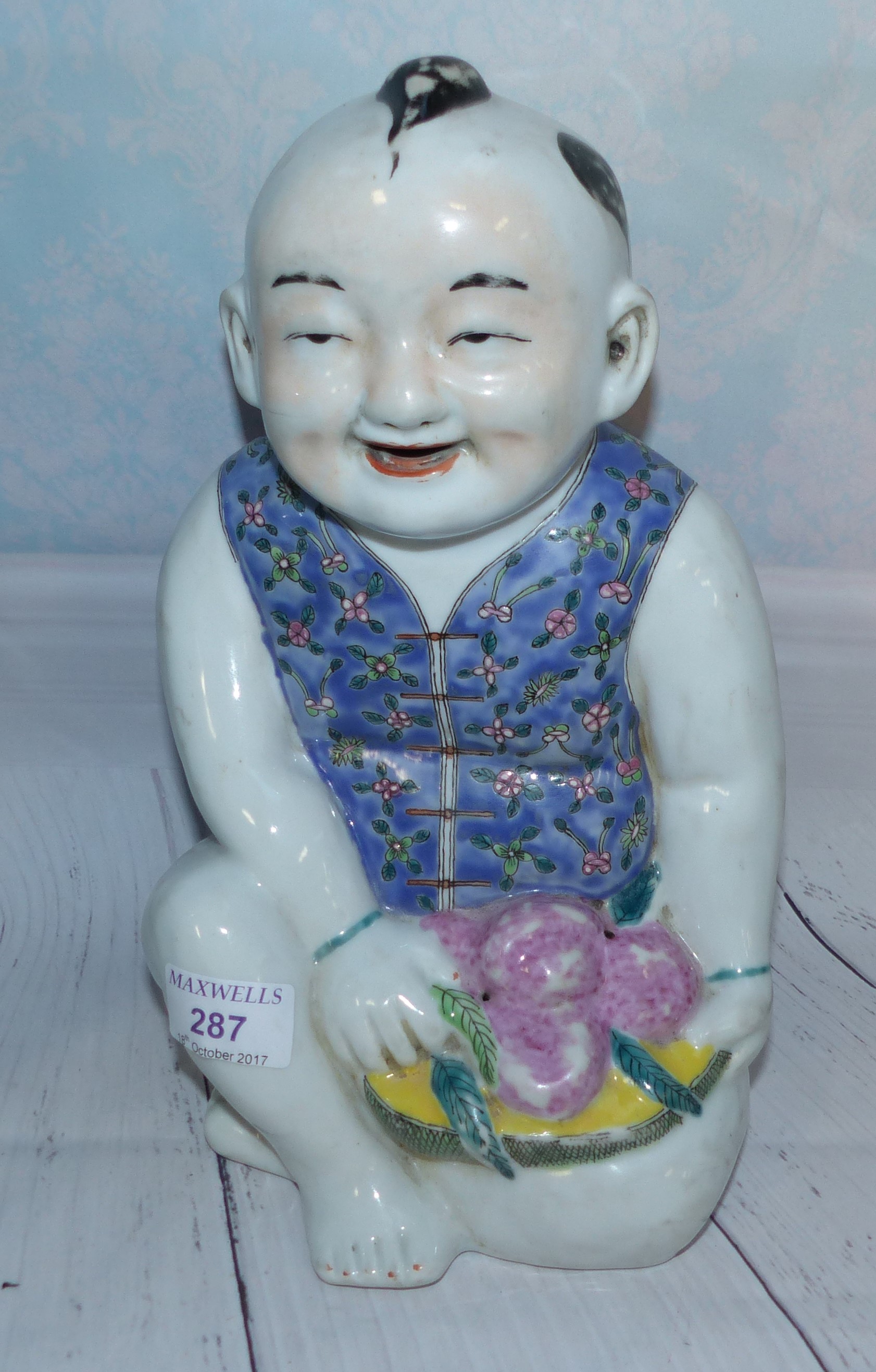 A large Chinese porcelain figure of a seated boy