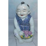 A large Chinese porcelain figure of a seated boy