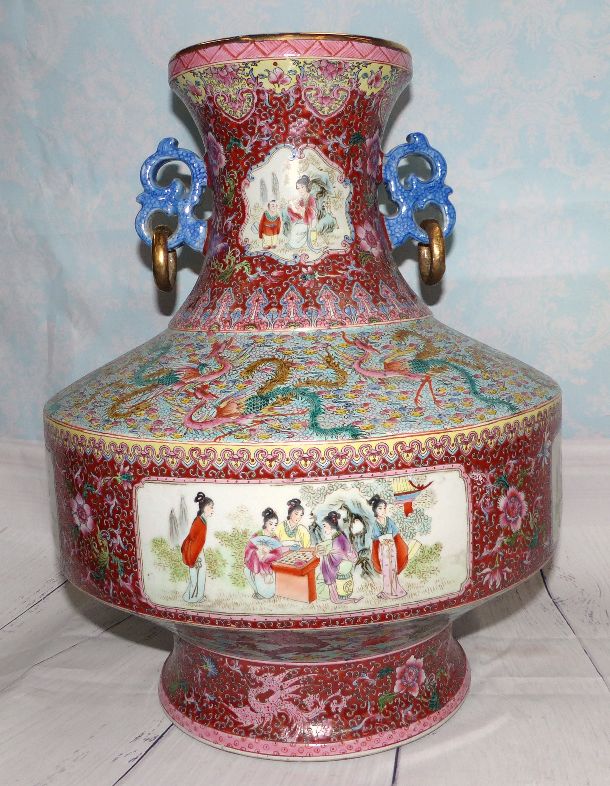 A Chinese porcelain famille rose urn with genre scene panels and ornate bands of dragon and floral