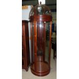 A mahogany cylindrical display case with dome top, enclosed by 4 full height carved glass panels,