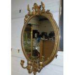 A 19th century Adam style gilt framed oval wall mirror with crest and triple sconces (with