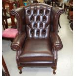 A Georgian style wing back armchair in deeply buttoned and studded brown hide