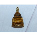 A Buddha pendant carved from a tiger's eye, set in 18 carat gold mounts