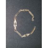 A bracelet formed from alternating trombone and reef knot links, stamped '9K'