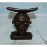 An African headrest with carved mask support