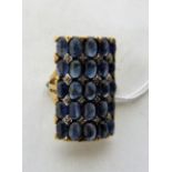 A sapphire and diamond cluster dress ring set with 25 sapphires en-cabochon and 16 diamonds. In gold