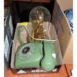 An Ericsson LM green telephone and an anniversary clock under a glass dome