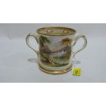 An early 19th century pearlware loving cup, gilded and painted with a landscape to one side and