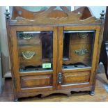 A late Victorian walnut smoker's cabinet, the pair of bevel glazed doors enclosing four drawers