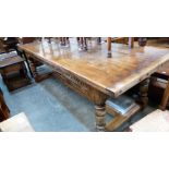 A fine quality joined oak refectory dining table, the cleated plank top over carved frieze, on