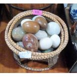 A woven basket of hardstone and treen eggs