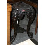 An Oriental hardwood pot stand on carved anthropomorphic supports