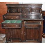 An oak carved sideboard with raised back over two drawers and cupboard enclosed by a pair of linen