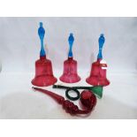 Three Victorian graduated cranberry glass bells with blue glass handles, the largest 13'' high,