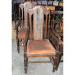 A pair of oak Carolean style elbow chairs with caned splats and scrolled arms