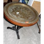 A wrought iron based occasional table with Benares type brass tray top