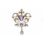 EDWARDIAN AMETHYST AND SEED PEARL SET BROOCH PENDANT of sinuous openwork form and set with a