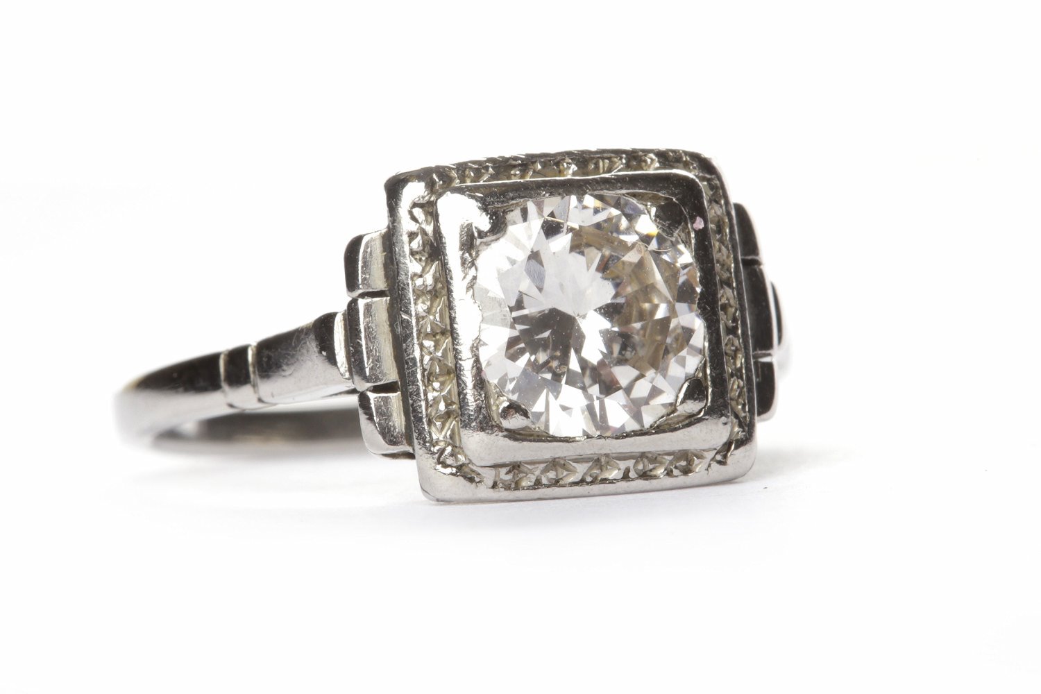 ART DECO DIAMOND SOLITAIRE RING the square bezel with engraved border and set with a round