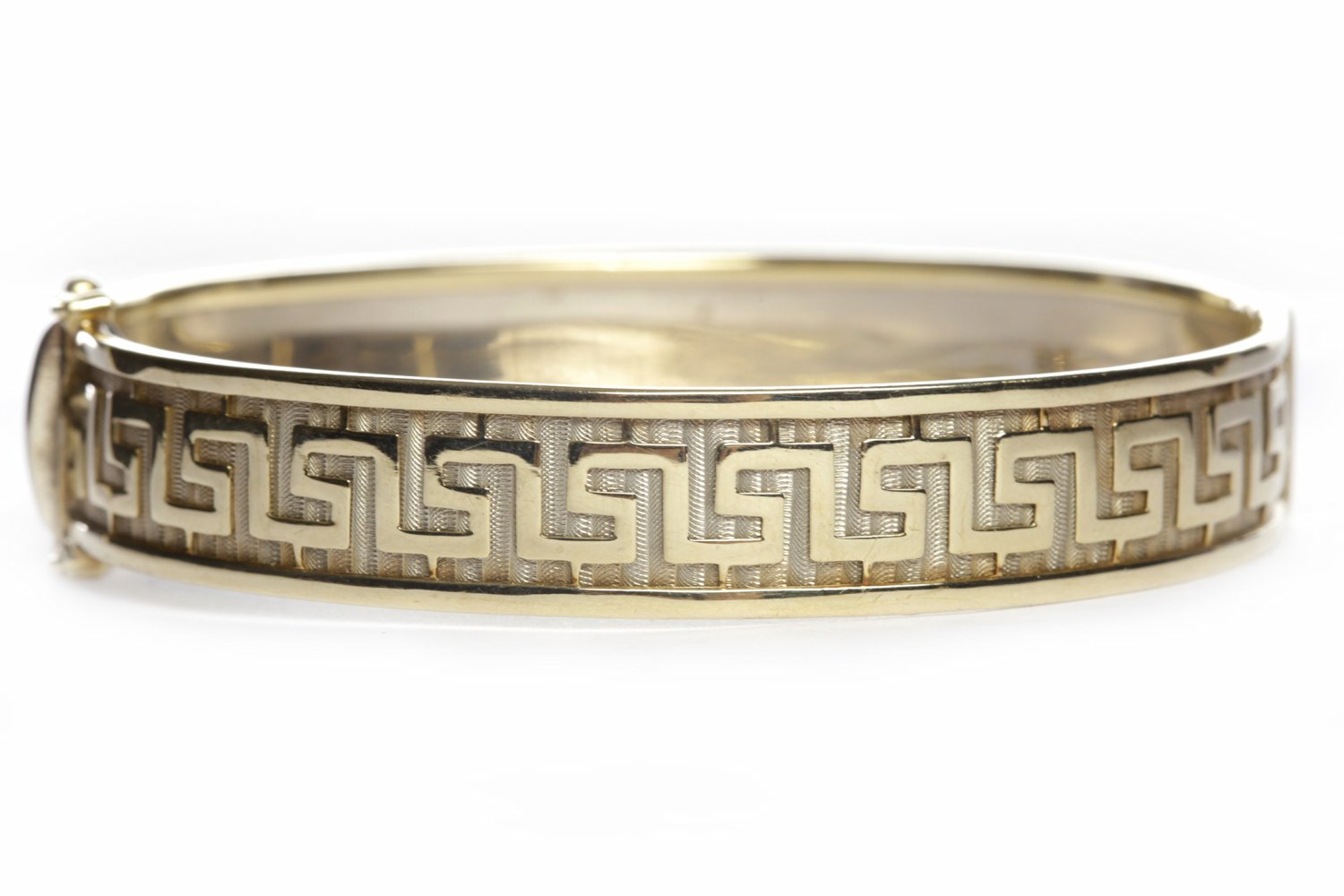 NINE CARAT GOLD BANGLE of oval form, with Greek key pattern decoration, 61mm across, 19.