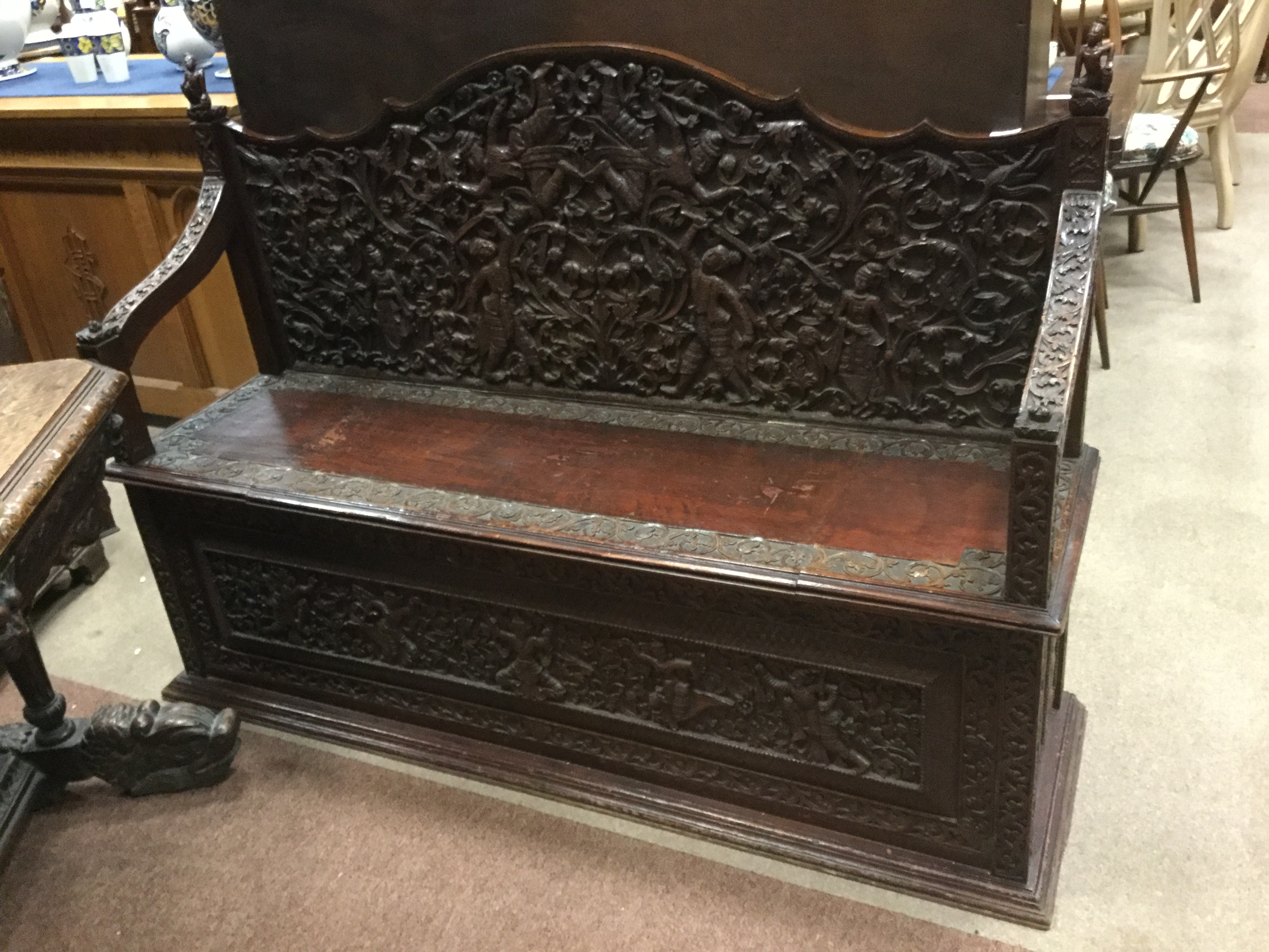 LATE VICTORIAN CARVED OAK HALL SETTLE IN THE ANGLO-INDIAN MANNER the shaped arched back panel